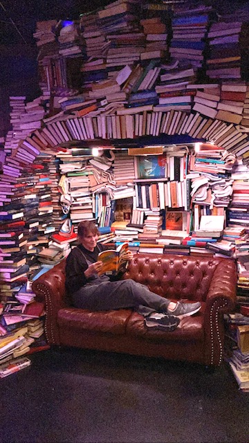 Gail Sailer reading on a couch, surrounded by books.